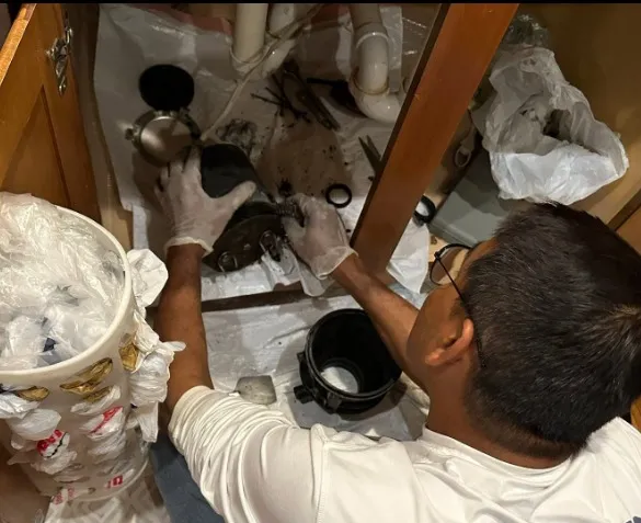 Technician repairing a leaking garbage disposal under a kitchen sink in Klamath Falls, OR.