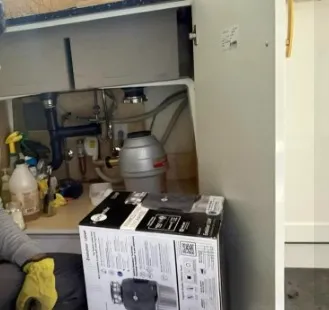 Technician repairing a garbage disposal making loud grinding noises in Klamath Falls, OR.