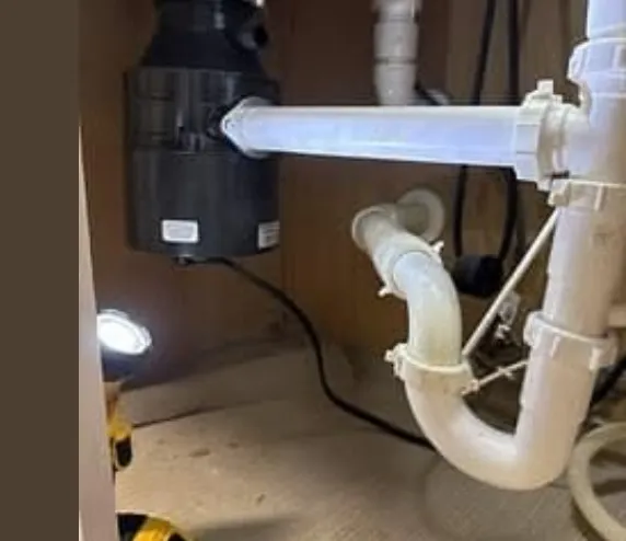Technician repairing a jammed garbage disposal in a Klamath Falls, OR kitchen.