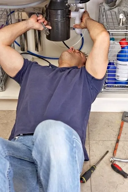Technician repairing a slow-draining kitchen sink caused by a clogged garbage disposal in Klamath Falls,